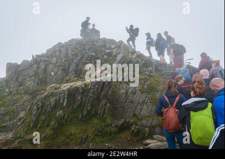 Snowdon, Großbritannien. 08/07/2020. Lockere Pandemiesperrregeln führten zu einer Zunahme von „tay-cations“. Touristen in der Warteschlange für ihre Reihe zu Peak für Selfie zugreifen. Stockfoto