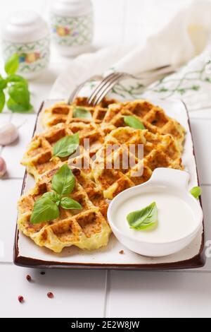 Hausgemachte Zucchini Waffeln mit Käse, Sause und Blatt Basilikum auf weißem Hintergrund. Konzept der Keto Ernährung Lebensmittel. Selektiver Fokus. Stockfoto