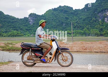 Happy Vietnamese Mann Reiten Honda Dream II Motorrad / Motorrad auf dem Land, Ninh Bình Provinz, Vietnam Stockfoto