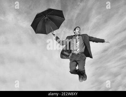 Schwarz-Weiß-Foto des fallenden Geschäftsmann mit Regenschirm Stockfoto