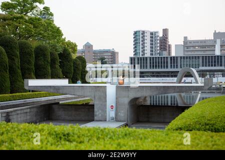 Das Cenotaph im Hiroshima Peace Memorial Park, Hiroshima, Japan, am frühen Abend. Blick auf das Museum. Stockfoto