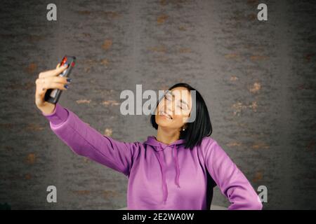 Fröhliche junge Brünette Frau nimmt Selfie mit Smartphone Stockfoto