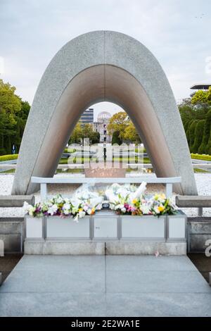 Das Cenotaph im Hiroshima Peace Memorial Park, Hiroshima, Japan, am frühen Abend. Blick durch das Cenotaph zum Hiroshima Friedensdenkmal. Stockfoto