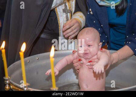 Kleines Mädchen taufte in der Kirche und badete in einer Schüssel zur Taufe. Stockfoto