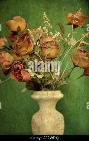 Eine Blume weiße Vase mit einem Bouquet von Herbst braun gefärbte künstliche Rosen auf grünem Hintergrund. Vorderansicht, vertikal, Vintage-Stil Stockfoto