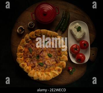 Italienische Pizza mit Schinken und Mozzarella gefüllte Kruste auf einem Holzbrett Stockfoto