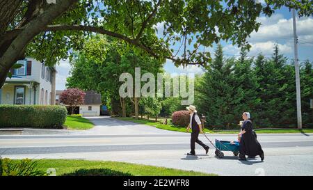 Gordonville, Pennsylvania, Juni 2020 - eine Amish Familie, die entlang einer Landstraße einen Wagen zieht, mit einem kleinen Kind darin Stockfoto