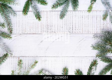 Weihnachtlicher Hintergrund mit Tannenzweigen, Tannenzweigen, Geschenkschachtel, getrockneten Orangen, Sternanis und Beeren auf dem alten weißen Holzbrett. Draufsicht. Stockfoto