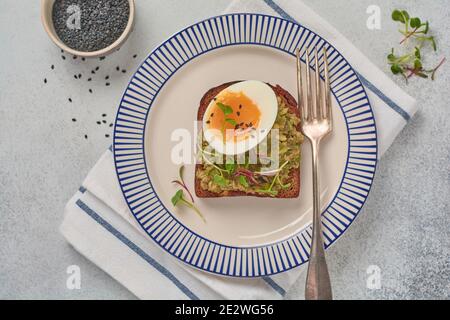Gesundes Sandwich mit Avocado, Eiern und Microgreens auf einem Servierteller zum Frühstück. Gesunde Ernährung Ernährungskonzept. Draufsicht. Stockfoto