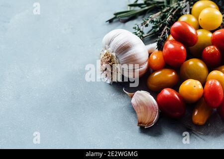 Tomaten, Knoblauch und Kräuter auf einem Holzbrett Stockfoto