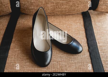 Leder schwarze Damenschuhe auf einem braunen Stoff. Modekonzept, Damenschuhe, Accessoires. Stockfoto