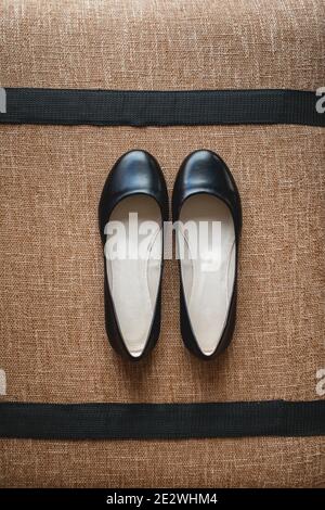 Leder schwarze Damenschuhe auf einem braunen Stoff. Modekonzept, Damenschuhe, Accessoires. Stockfoto