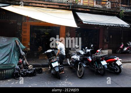 Arbeiter parkt Motorrad vor der Autowerkstatt in Talat Noi Stockfoto