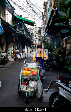 Verkäufer schiebt Fruit Cart entlang der Straße in Talat Noi Alley In Bangkok Stockfoto