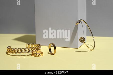 Moderne goldene Armbänder und Ring auf gelbem Hintergrund Stockfoto