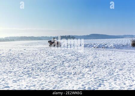 Geländefahrzeug in Bewegung im Winter. Quad-Biker auf dem märz. Reisen. Tourismus. Quad-Fahrer fährt über ein gefrorenes Feld in der Tschechischen Republik Stockfoto