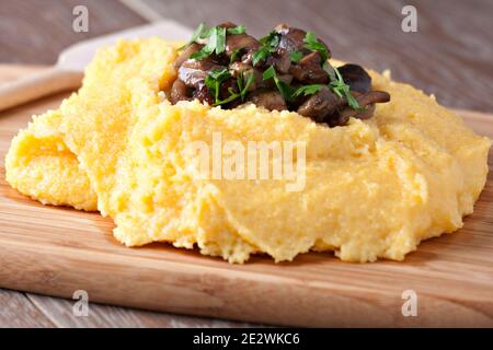 Polenta mit Pilzen. Traditionelle Maisfutter auf dem Teller. Stockfoto