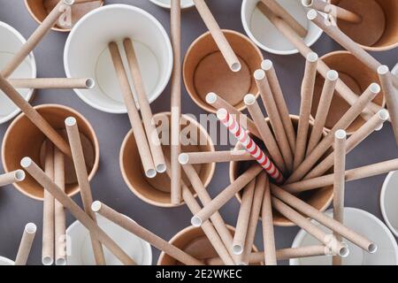 Trinkröhrchen Trinkhalme aus Papier und Maisstärke in leeren Pappkaffeetassen auf trendigem grauen Hintergrund. Zero Waste und Kunststoff frei Konzept. Stockfoto
