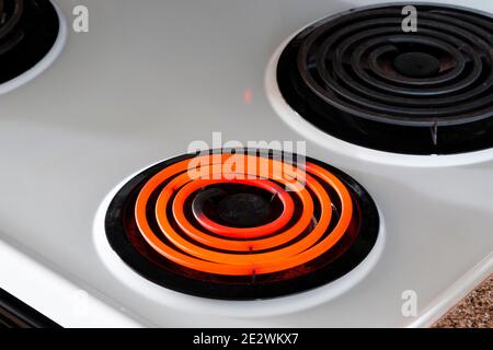 Horizontale Aufnahme eines weißen Herdplatten mit einem heißen Brenner und zwei davon. Aufnahme in einem Winkel. Stockfoto