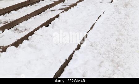 Schneebedeckte, rutschige Betontreppen. Erster Schnee auf Granitsteinstufen Stockfoto