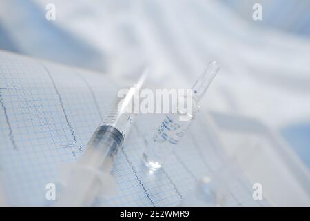 Medizinische Ampulle und Spritze auf dem EKG-Datensatz. Stockfoto