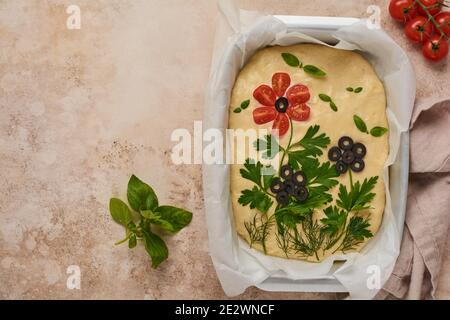 Hausgemachte Blume Focaccia. Rohe Focaccia kreativ mit Gemüse auf Pergamentpapier dekoriert. Sauerteig. Dekoriertes italienisches Brot. Stockfoto