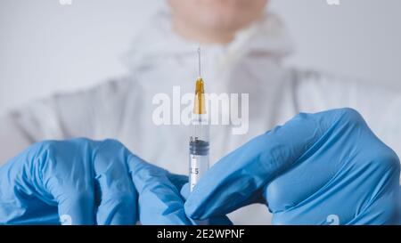 Arzt hält einen Coronavirus-Impfstoff in einer Spritze. Beendigung des Covid-19-Pandemiekonzepts. Stockfoto