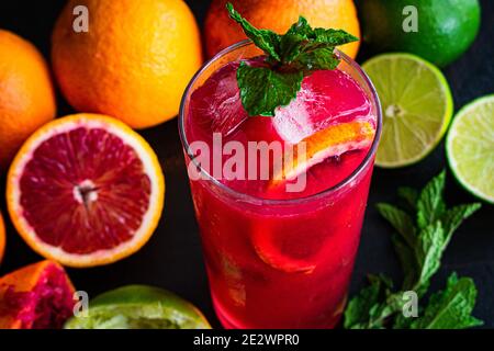 Blood Orange und Himbeer Mojito: Ein Rum-Cocktail mit Blutorangen, Himbeeren, Limetten und Minzblättern, serviert in einem hohen Glas über Eis Stockfoto
