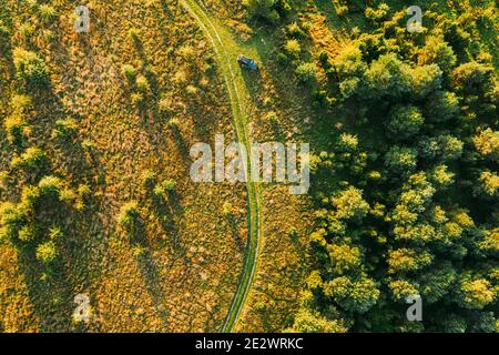 Luftaufnahme Des Autos In Der Nähe Der Country Road Thgrough Forest Und Green Meadow Landscape In Sunny Summer Morning. Top Blick Auf Die Schöne Europäische Natur Aus Stockfoto