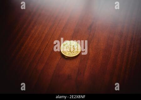 Eine einsame goldene Bitcoin-Gedenkmünze liegt auf einem Holztisch. Stockfoto