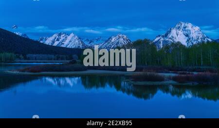 Faszinierende Aufnahme von schneebedeckten Bergfelsen und Bäumen reflektiert In einem See Stockfoto