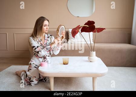 Attraktive Frau im Schlafanzug Anwendung Gesichtscreme. Attraktive junge Frau in Pyjama Anwendung feuchtigkeitsspendende Creme auf das Gesicht. Frisch vom Morgen Stockfoto