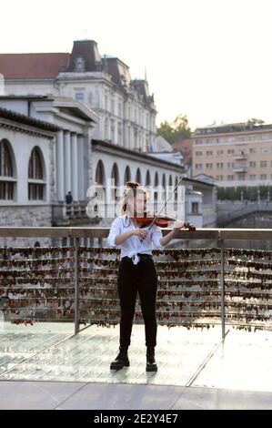 Straßenmusiker spielt die Geige auf der Metzgerbrücke, die ist Mit Liebesschlössern in der Stadt Ljubljana bedeckt Stockfoto