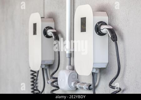 Elektrisches Ladegerät an Betonwand Stockfoto