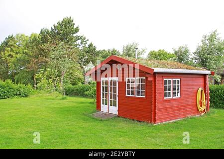 Roter Gartenschuppen mit grünem Dach Stockfoto