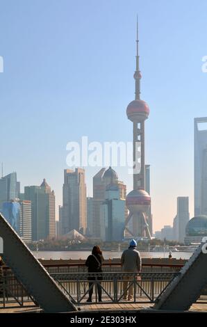 Stand auf der Waibaidu Brücke in Shanghai mit Blick auf die klassische Pudong Skyline. Zwei Passanten halten für Fotos an. Stockfoto