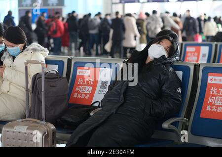 Suzhou.China-Jan.2021: Asiatische weibliche Reisende ruht auf Sitz im Bahnhof, in Gesichtsmaske, um Coronavirus während des Frühlingsfestes zu verhindern Stockfoto
