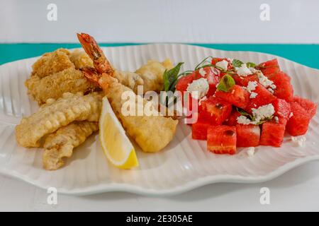 Zerschlagene Garnelen, Salat mit frischer Wassermelone, Minze und Feta-Käse und Zitrone. Serviert auf einer weißen Keramikplatte. Stockfoto