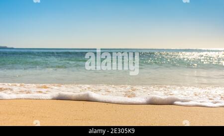 Wellen Sie sich an schönen sonnigen Tagen über den Sand Stockfoto