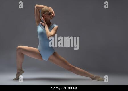 Junge Frau macht Gymnastik im Hintergrund im Studio Stockfoto