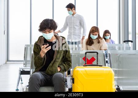 Reisende tragen Schutzmaske im internationalen Flughafen, während Covid-19 Pandemie, Sicherheit mit sozialen Distanzierungsprotokoll, neue normale Reise concep Stockfoto