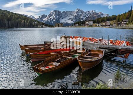 Misurina, Italien - 8. Oktober 2020: Der Misurina See mit touristischen Booten und Hotels und verschneiten Bergen der Dolomiten im Hintergrund, im Herbst, Stockfoto