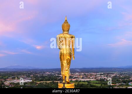 Golden Walking Buddha Statue auf einem Hügel oder Berg zu Wat Phrathat Khao Noi Tempel während der Dämmerung, Nan Provinz, Thailand Stockfoto