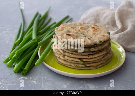 Weizen Roggen Vollkornfladenbrot mit grünen Zwiebeln auf grauem Hintergrund. Gesunde hausgemachte Speisen Stockfoto