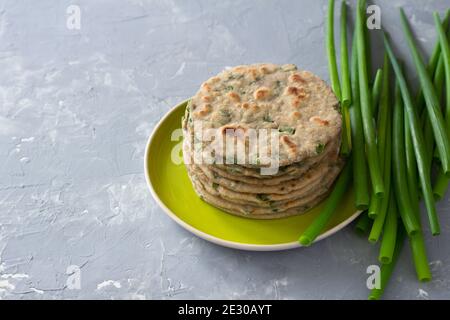 Weizen Roggen Vollkornfladenbrot mit grünen Zwiebeln auf grauem Hintergrund. Gesunde hausgemachte Speisen. Freiraum Stockfoto