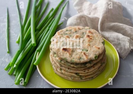 Weizen Roggen Vollkornfladenbrot mit grünen Zwiebeln auf grauem Hintergrund. Gesunde hausgemachte Speisen Stockfoto