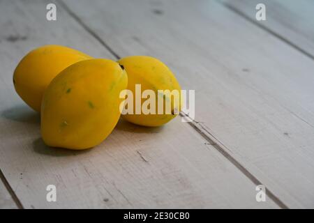 Ganze gelbe goldene Passionsfrucht, Passiflora edulis, auf Holztischplatte, Es ist eine reiche Quelle von Antioxidantien, Mineralien, Vitamine und Ballaststoffe. Stockfoto
