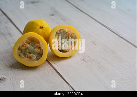 Bündel von gelben goldenen Passionsfrucht, Passiflora edulis, ganz und geschnitten, auf Holz Tischplatte, eine reiche Quelle von Antioxidantien, Mineralien, Vitamine, Ballaststoffe. Stockfoto