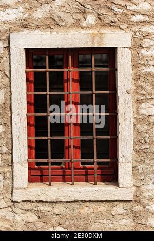 Nahaufnahme eines alten Fensters mit schmiedeeisernen Sicherheitsstangen an einer Steinmauer. Venetien, Italien, Europa Stockfoto