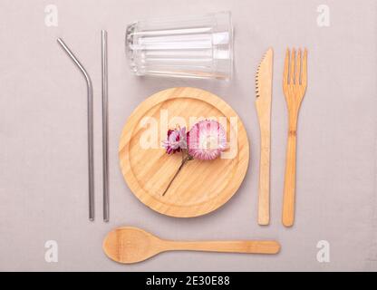 Kein Abfall, Kunststoff-freies Konzept. Holzteller, Glastasse, Set aus Bambus Besteck. Flat Lay auf Textil Leinen Hintergrund - Bild Stockfoto